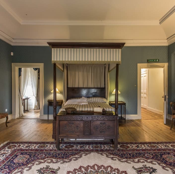 A beautiful bedroom featuring a wooden floor, a cozy carpet, and two doors, with soft lighting creating a warm and inviting atmosphere.