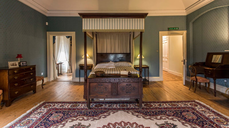 A beautiful bedroom featuring a wooden floor, a cozy carpet, and two doors, with soft lighting creating a warm and inviting atmosphere.