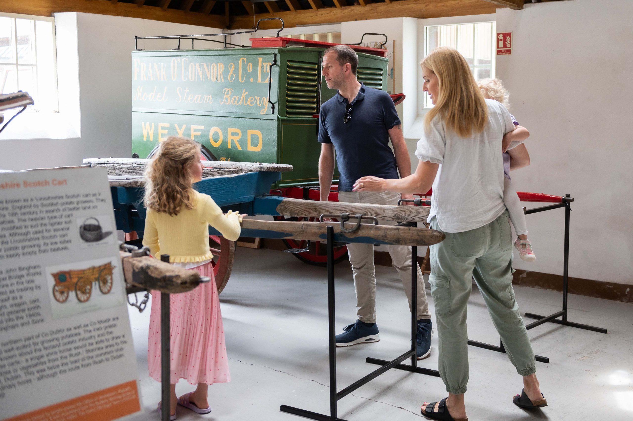 Parents with two young children looking at historic trailer in Agricultural Museum