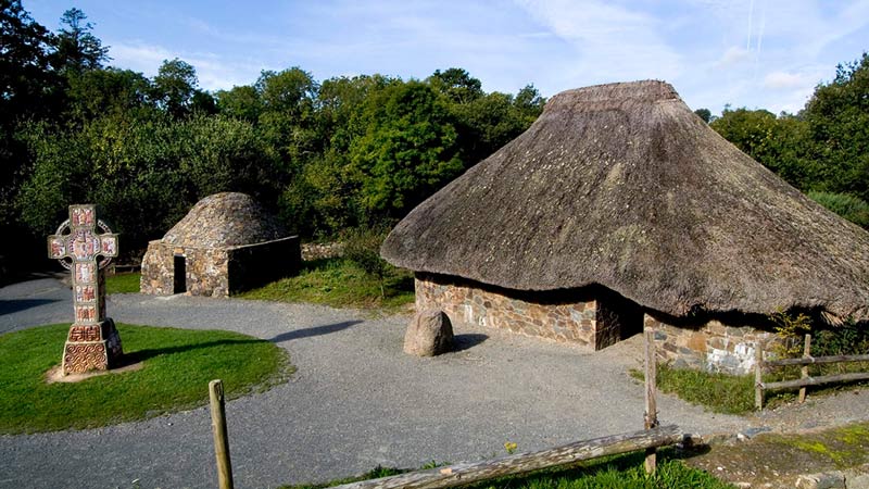Traditional stone-built huts with thatched roofs set in a wooded parkland at Johnstown Castle, Ireland.